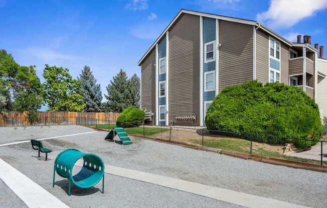 A playground with a slide and a green slide in front of a building.