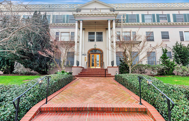 A brick pathway leads to a building with a large front door.