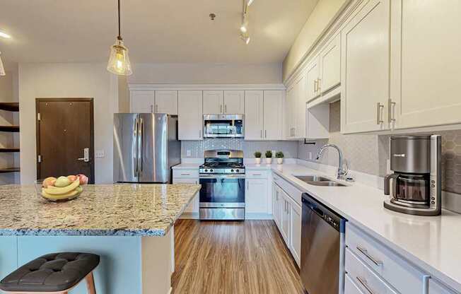 A kitchen with a granite countertop and stainless steel appliances.