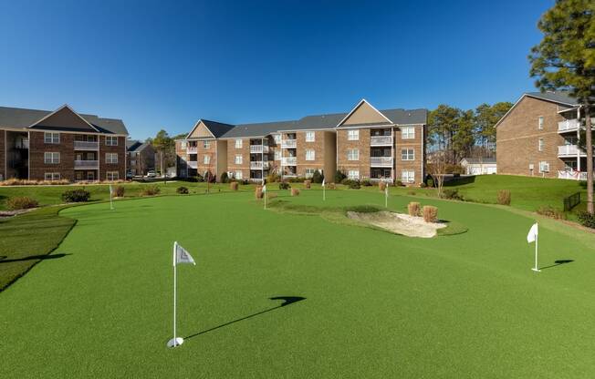 a putting green with apartments in the background