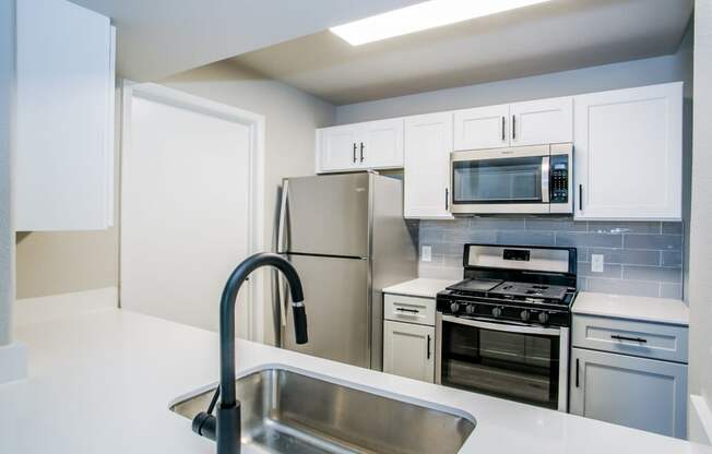 a kitchen with white cabinets and stainless steel appliances