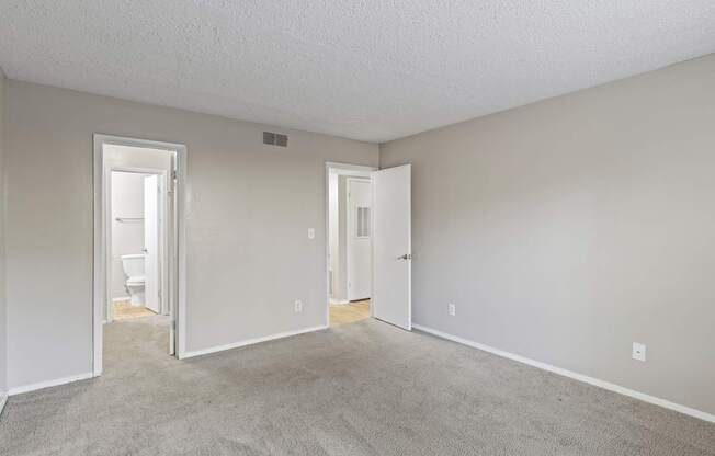 A room with a carpeted floor and two doors.