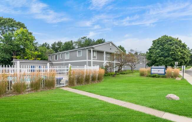 a gray house with a yard and a white fence