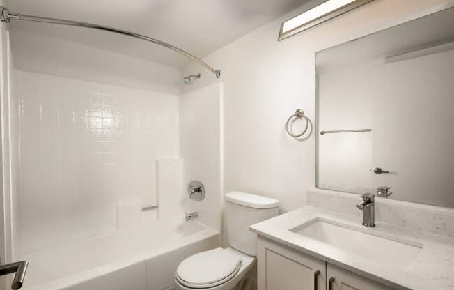 A white bathroom with a toilet, sink, and tub.