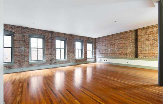 an empty room with brick walls and wood floors