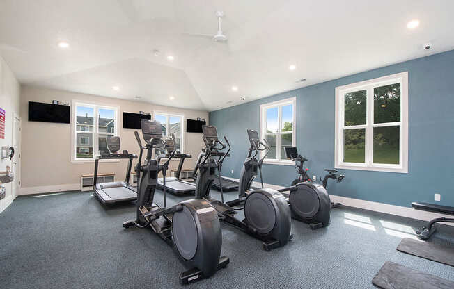 fitness center with plenty of cardio equipment and windows at The Crossings Apartments, Michigan, 49508