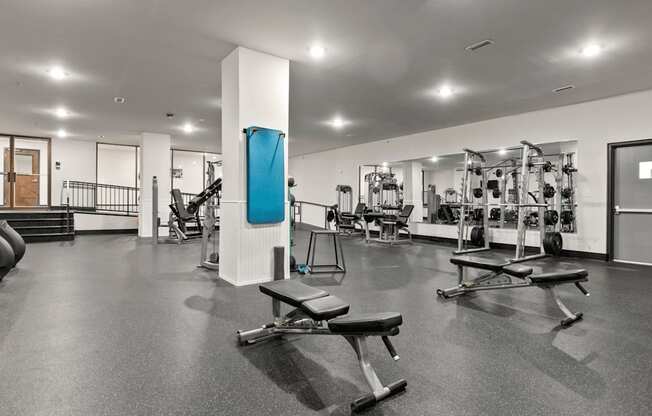 A gym with a variety of equipment including weights and benches.