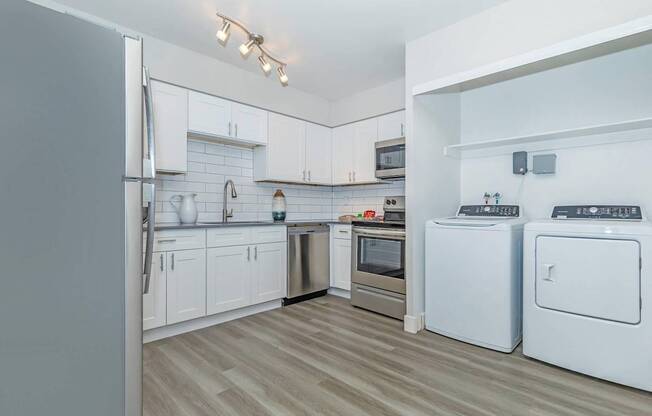 A modern kitchen with white appliances and wooden flooring.