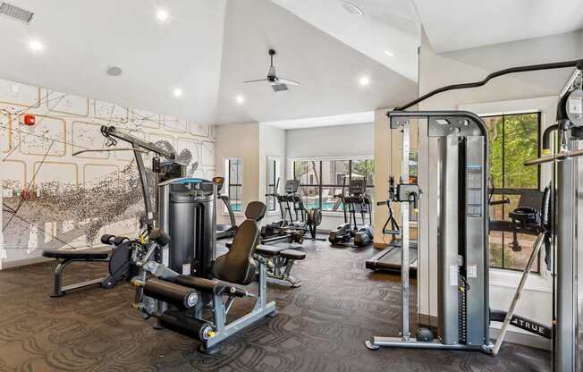 A gym with a variety of equipment including a weight bench, a leg press machine, and a cable machine.