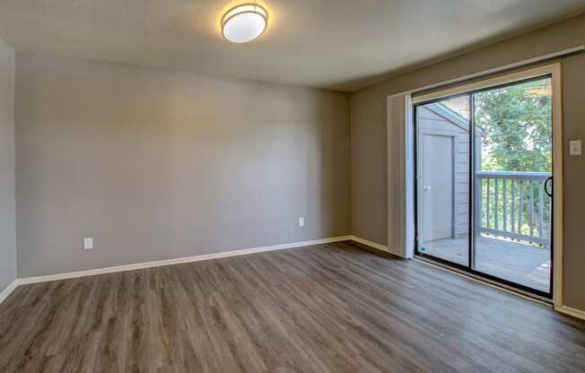 an empty living room with a sliding glass door to a balcony