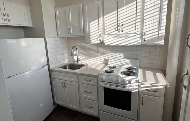 A kitchen with white appliances and cabinets.