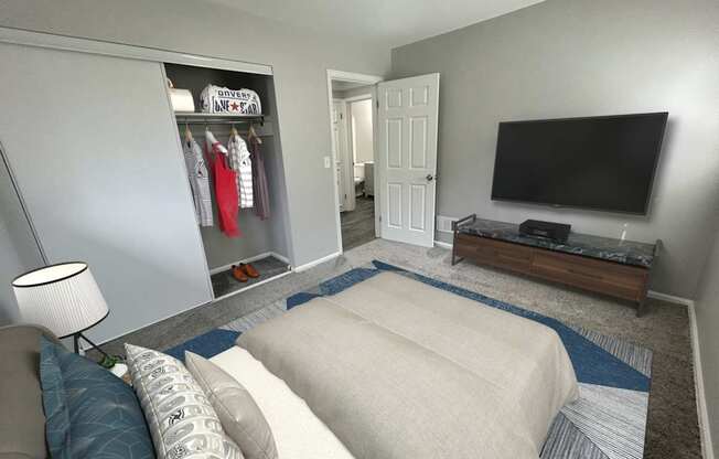 A living room with a couch, a television, and a clothing rack.