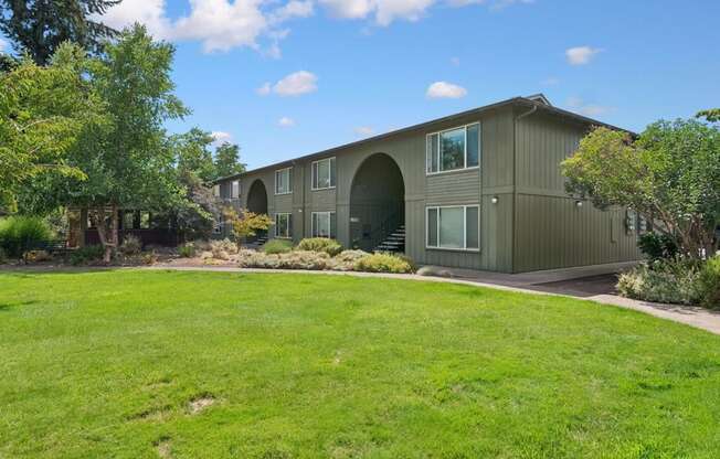 A green lawn in front of a grey building.