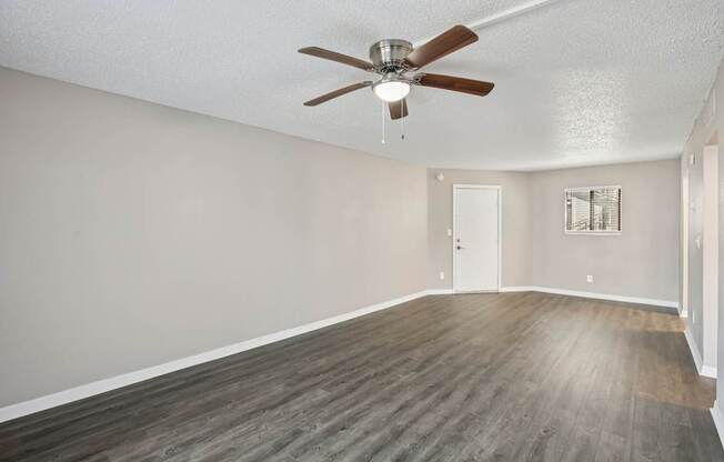 A room with a ceiling fan and wooden flooring.
