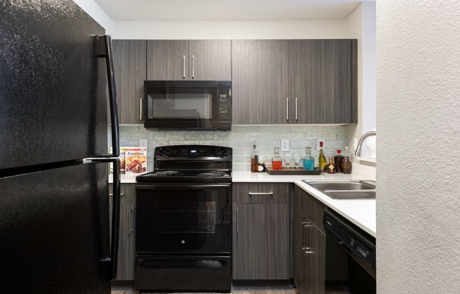 a kitchen with black appliances and dark wood cabinets