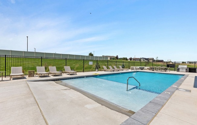 a swimming pool with chairs and a fence around it