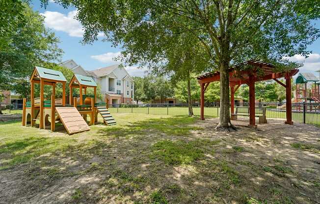 A playground with a swing set and a treehouse in a park.