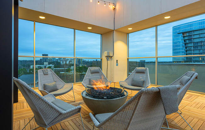 a patio with a fire pit and chairs on a balcony with large windows