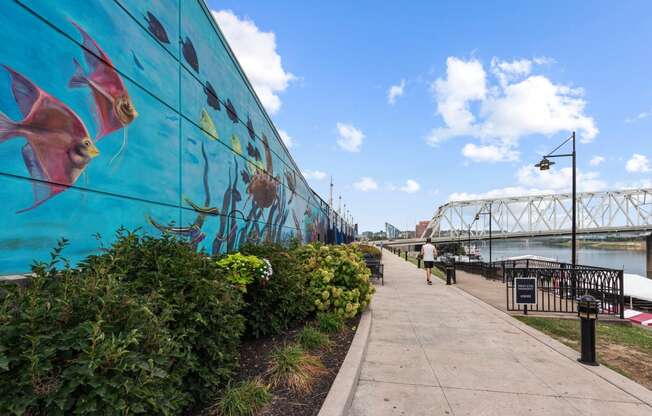 a large mural on a wall next to a river with a bridge