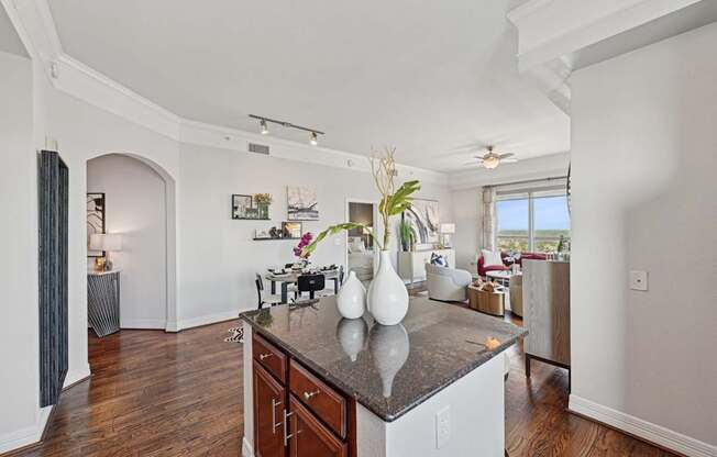 Model kitchen with a dark counter top and wooden floors at Dominion Post Oak apartments in Houston, TX