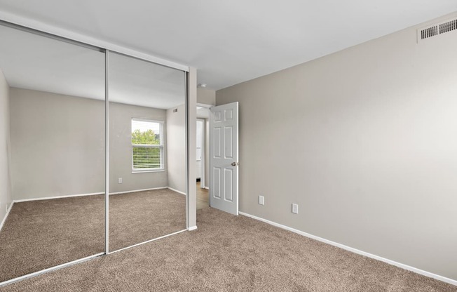 Bedroom with a mirrored closet and carpeted floors at Creve Coeur, Creve Coeur, MO