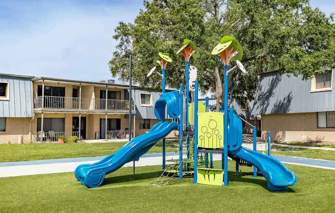A playground with a blue slide and yellow and green towers.