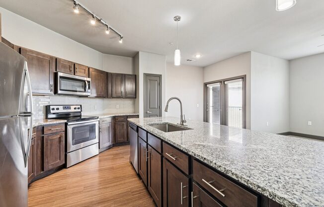 A kitchen with a granite countertop and stainless steel appliances.