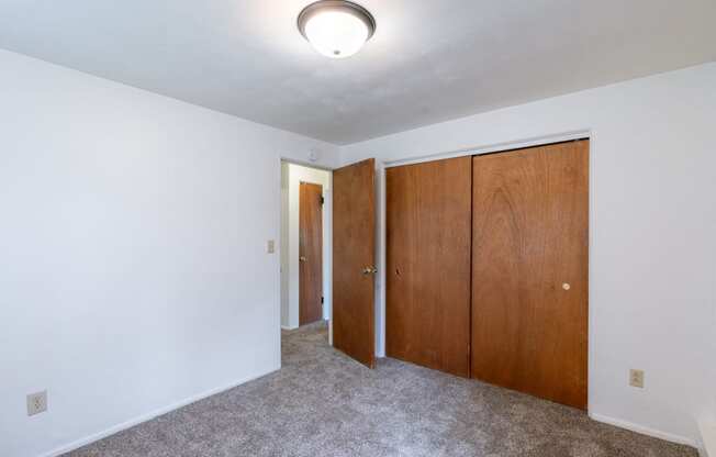 a bedroom with white walls and wooden doors and a ceiling light. Fargo, ND Spring Apartments