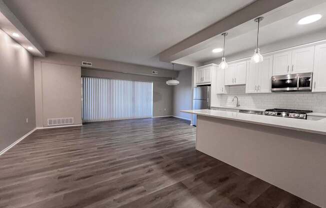 an empty living room and kitchen with white cabinets