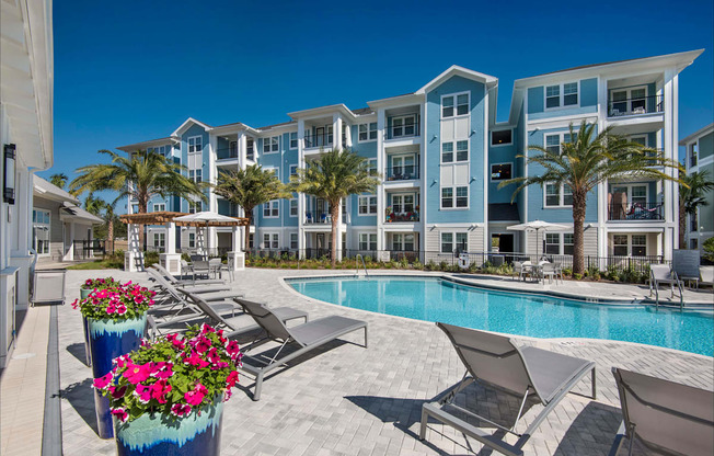 A pool area with lounge chairs and a building in the background.