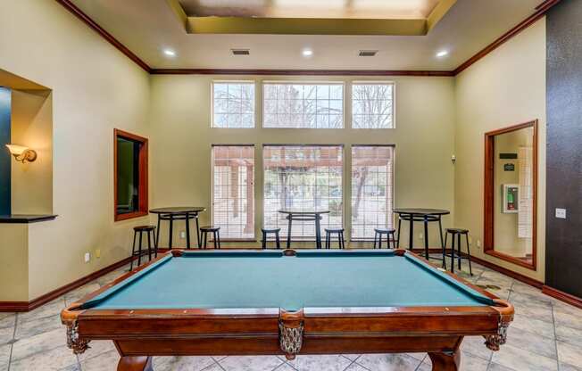 a pool table in the corner of a room with a large window