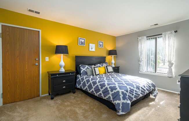 a bedroom with a bed and a yellow wall and a window