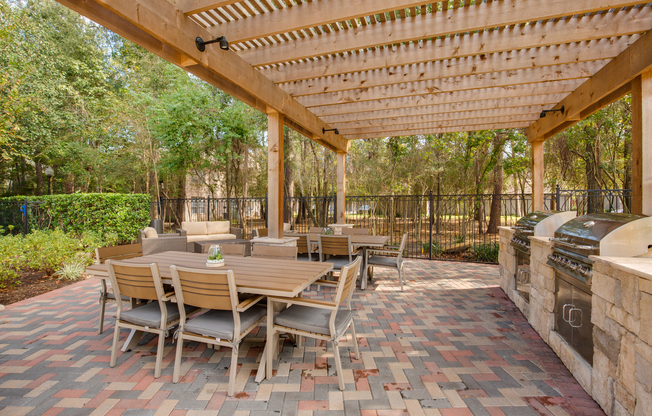 View of Grilling Area with Tables, Chairs, and Landscaping at Raveneaux Apartments