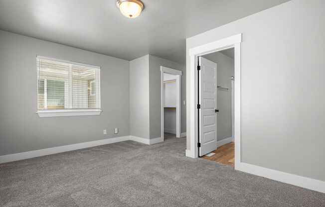 a bedroom with a door to a closet and a window