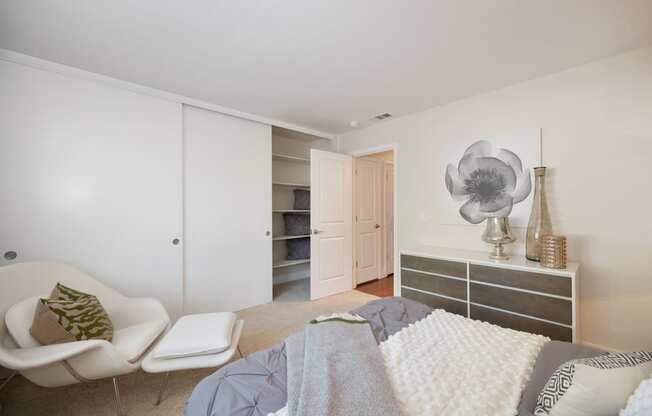 a bedroom with a bed and lounge chair at Folsom Ranch Apartments in California