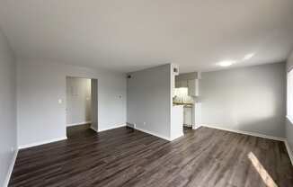 a living room and kitchen with wood flooring and white walls