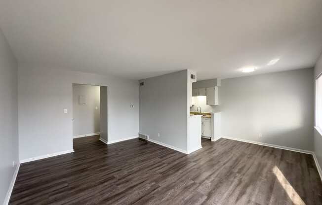 a living room and kitchen with wood flooring and white walls