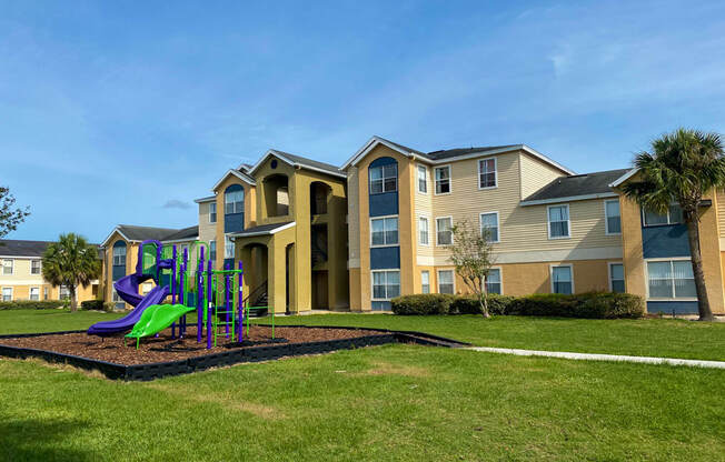 Building Exterior surrounded by shrubs and palm trees with playground view