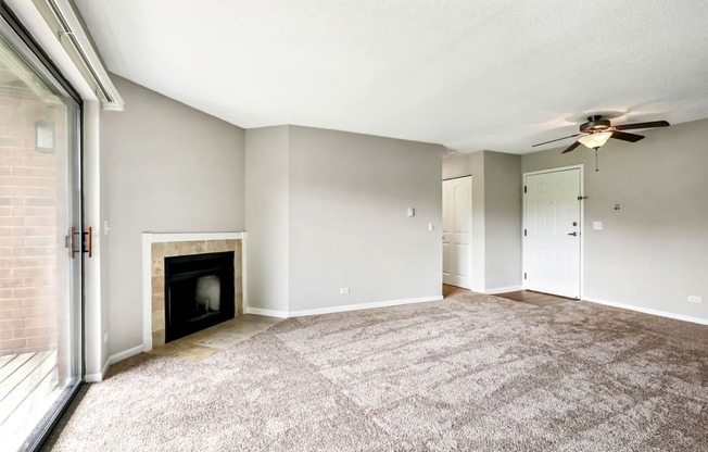 an empty living room with a fireplace and a ceiling fan