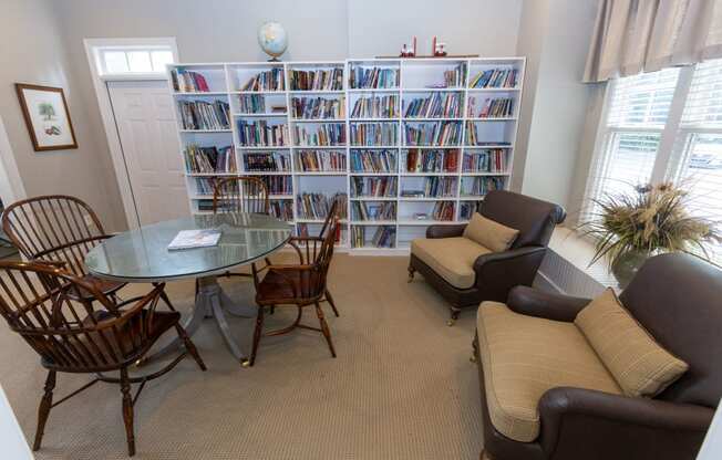 a living room with a table and chairs and a book shelf