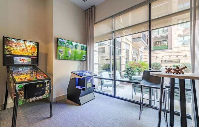 A room with a pinball machine and a TV showing a game.