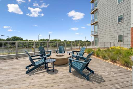 A wooden deck with blue chairs and a table at The Waterford At Rocketts Landing Apartments, PRG Real Estate, Richmond, Virginia