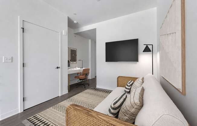 A modern living room with a couch, a chair, a desk, and a television.