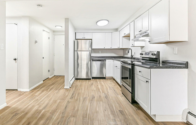 Chic modern kitchen with sleek stainless steel appliances, elegant white cabinetry, and warm wood flooring.