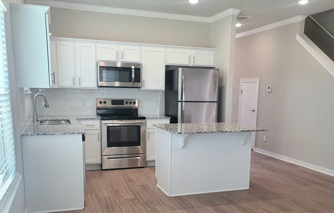 B4 Kitchen with laminate wood flooring, granite countertops, and stainless steel appliances