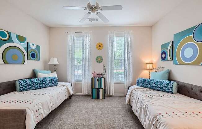 A bedroom with two beds and a ceiling fan.