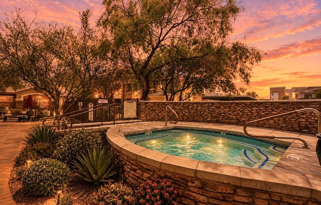 A pool surrounded by a stone wall and plants.