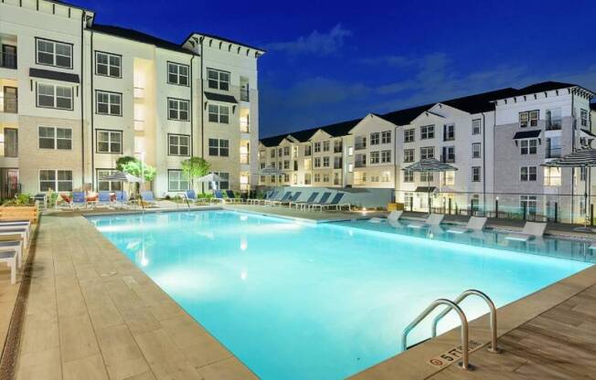 a swimming pool with lounge chairs and umbrellas next to a building at The Eddy at Riverview, Smyrna