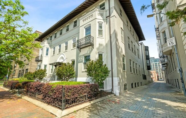 a grey apartment building with a brick sidewalk in front of it