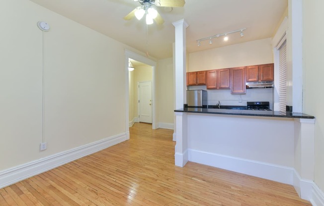 vacant living area with hardwood floors, view of kitchen and ceiling fan at dupont apartments in washington dc